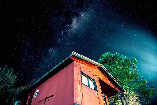 casilla rosada junto a arboles en isla del delta de rio Paran&aacute; con fondo de estrellas y v&iacute;a l&aacute;ctea