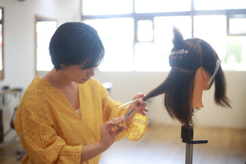 	髪を切る練習する美容師　イメージ