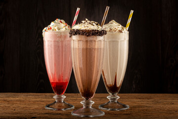 Three glasses of milkshake with assorted flavors. Chocolate, vanilla and strawberry milkshake.
