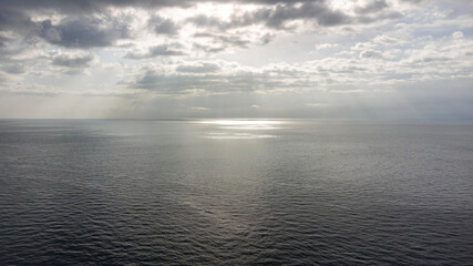 sun shining through clouds in the middle of the ocean