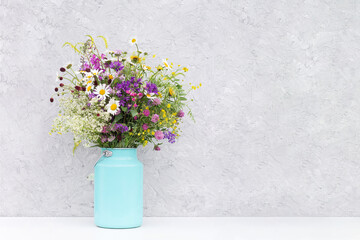 Bouquet of bright wild flowers in tin can vase on background gray stone wall. Template for postcard. Concept Women's day, Mothers Day, Hello summer or Hello spring