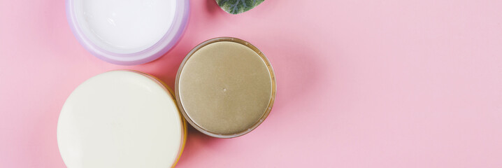 Mockup cosmetic jar with cream or lotion and leaf isolated on pink background, mock up package for advertising, skincare or cosmetology, top view, flat lay, skin care and treatment with product.