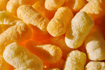 Closeup of puffcorn under sunlight. Sweet snack corn puffs. Macro of puffed corn - obrazy, fototapety, plakaty