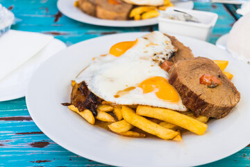 Baked meat, french fries, fried eggs and onion. Protein meal.