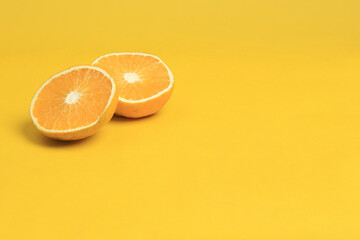 Naranja cortada en dos partes sobre fondo Amarillo y con espacio a la derecha para Texto. Toma Horizontal de naranja partida sobre amarillo. Primer Plano de Naranja madura y jugosa