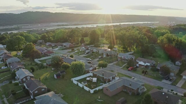 A slow forward dusk aerial establishing shot of a typical rust belt Pennsylvania neighborhood. Pittsburgh suburbs. Ohio River in the distance.  	
