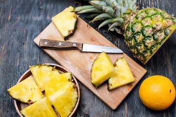 pineapple on a dark wooden table and pineapple slices on a cutting board