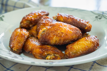Dish of grilled chicken wings over wooden table background.