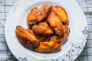 Dish of grilled chicken wings over wooden table background.