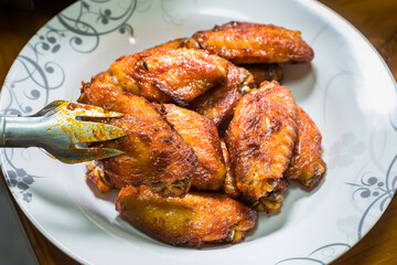 Dish of grilled chicken wings over wooden table background.