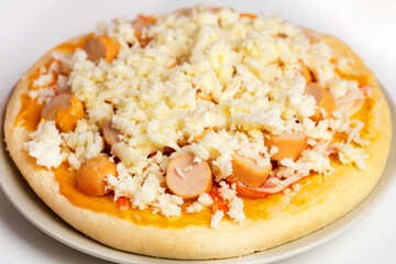 Pizza with mozzarella cheese, crab sticks, sausages and sauce, placed in a gray plate during preparation before being put into the oven, Cooking homemade