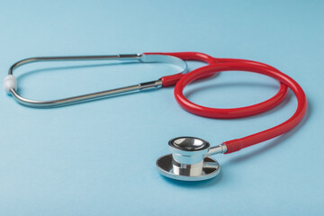 Medical stethoscope in red on a blue background.