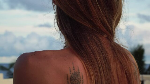 Pretty girl stroking shoulders and showing tribal tattoos on her bare back. Gimbal, close up