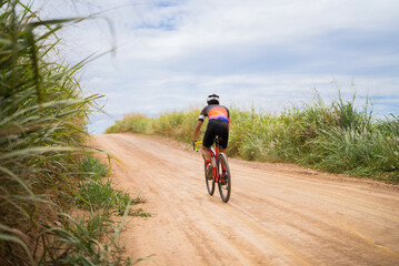 Asian man cycling on gravel road.