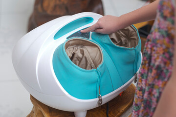Electric massager. Finger of a girl turn off a foot massager for relaxation. Energy saving.