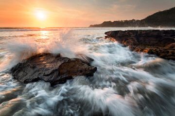 waves splashing around rocks at sunrise