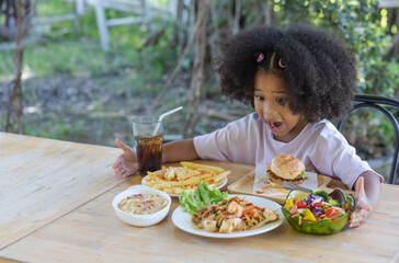 Childhood and healthy concept - Little African American curly hair girl excited about the various food on the table.