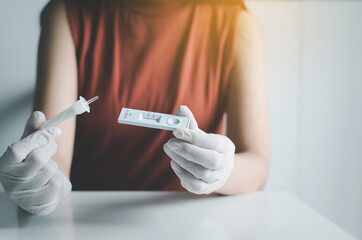 Asian patient woman using a covid-19 self test rapid antigen testing kit at home