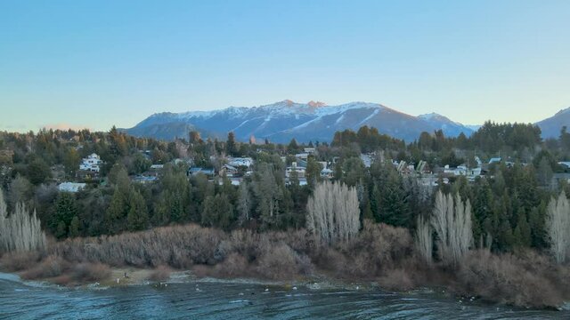 Flying over Lake Nahuel Huapi from the City of Bariloche, surrounded by its forest and mountains during the winter.