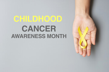 Childhood Cancer Awareness month, hand holding Gold Yellow Ribbon for supporting people living and...