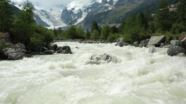 Forward ascending flight over a river slowly reviling a beautiful Morteratsch glasier mountain panorama 