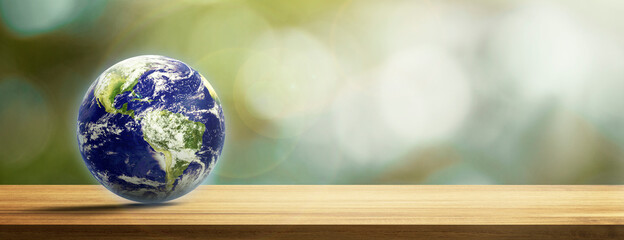 Earth on wood table in blurry background,nature orange bokeh and sunlight in morning. green planet on deck with copy space. Elements of this image furnished by NASA