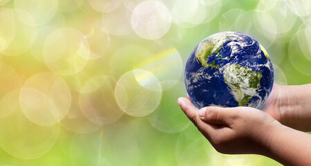 Earth on baby hand in blurry background,nature orange bokeh and sunlight in morning. green planet with copy space. Elements of this image furnished by NASA