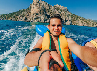 happy man rides a banana boat on a vacation on the sea