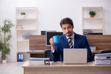 Young male employee drinking coffee during break