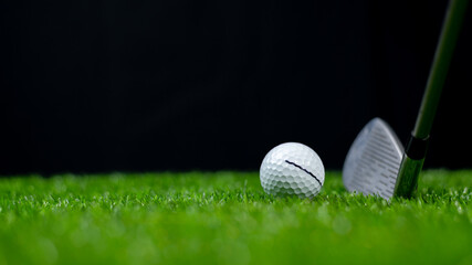 The Golf club and white golf balls on green grass for golfer training with blur golf course background, green tree sun rays with black background.