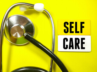 Medical concept.Text SELF CARE with stethoscope on yellow background.