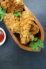 Fresh, hot, crispy deep fried chicken served on a white plate with tomato ketchup and mayonnaise. Chicken snack, hot fried chicken wings. Fast food over moody dark black background with copy space.