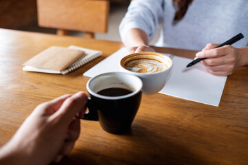 Closeup image of a couple people clinking coffee cups while working together