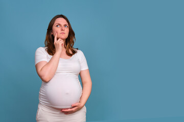 Portrait of a sad pregnant woman looking away on a blue background