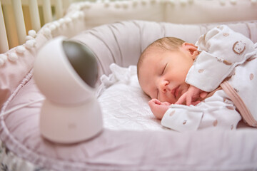 A home surveillance camera looks at the crib with a sleeping newborn baby - obrazy, fototapety, plakaty