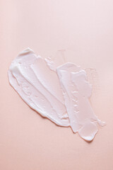 White cosmetic cream smears on a beige background. Skin care lotion serum texture sample. Closeup of a sample of a cosmetic product.