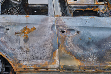 Burnt-out rusty cars on a city street, vandalism. Setting fire to cars by vandals and damage to property
