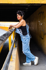 Mid adult afro mexican woman leaning on a guard rail at the entrance of a tunnel, relaxing