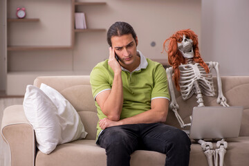 Young man sitting on the sofa with female skeleton