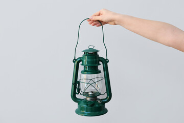 Hand with oil lamp on light background