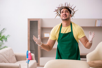 Young male contractor wearing prickly wreath on head cleaning th