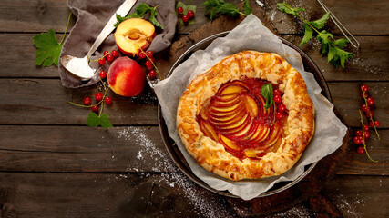 Peach gallete on baking paper on wooden background. Freshly prepared homemade pie.