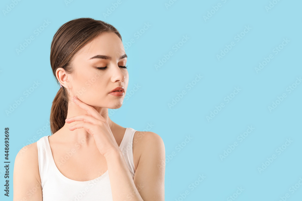 Wall mural Beautiful young woman massaging her face on color background