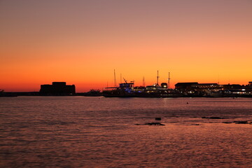 Fototapeta premium Silhouette view at paphos sea bay, castle and harbor, sunset time