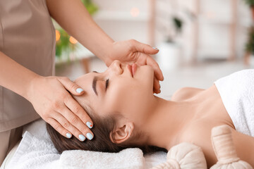 Fototapeta na wymiar Young woman receiving face massage in beauty salon