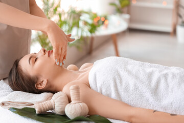 Obraz na płótnie Canvas Young woman receiving face massage in beauty salon