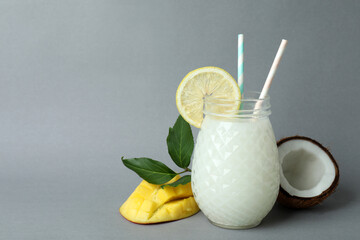 Glass of tropical cocktail and ingredients on gray background