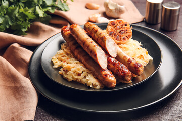 Plate with tasty grilled sausages and sauerkraut on dark background, closeup