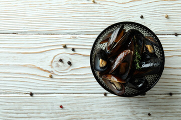 Bowl with fresh mussels on white wooden background
