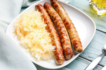 Plate with tasty sauerkraut and grilled sausages on color wooden background, closeup